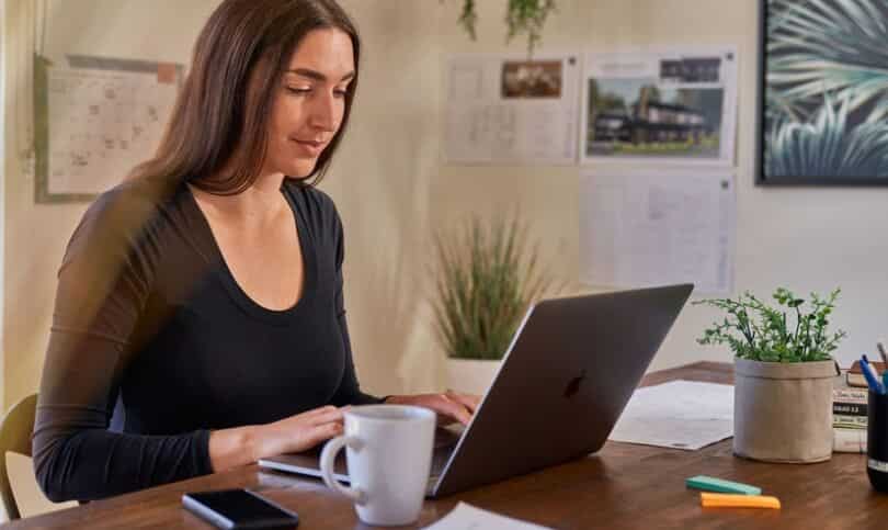 A builder sits at her desk using her laptop to plan a project.