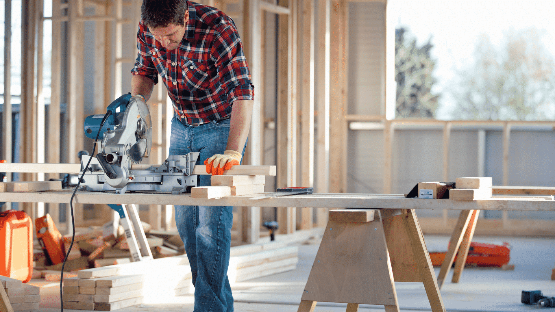 A builder works on an interior wall frame for a house under construction.