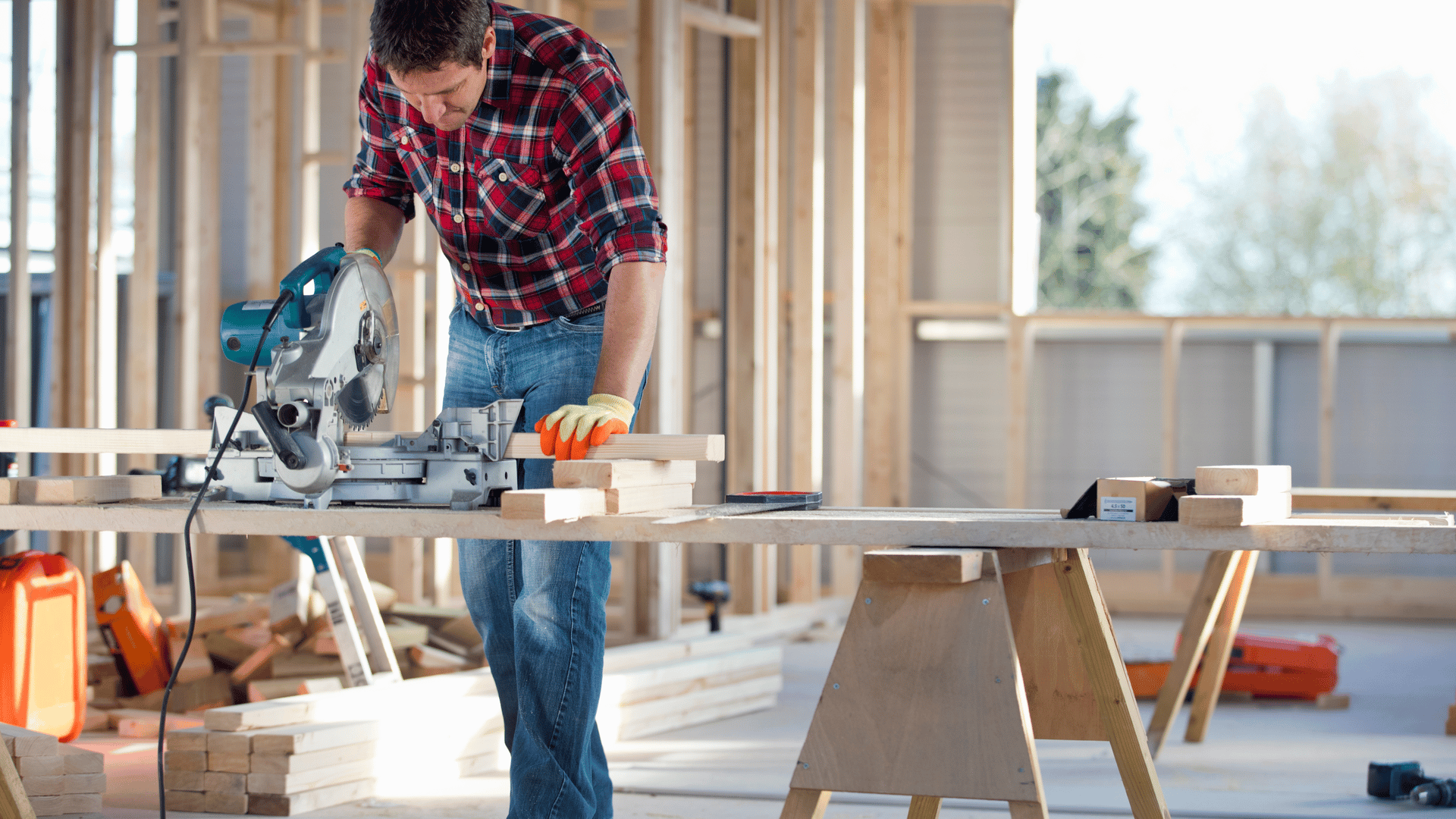 A builder works on an interior wall frame for a house under construction.