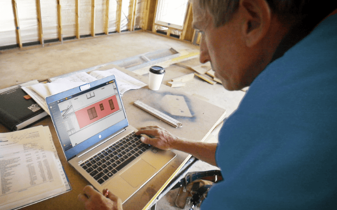 A builder using the Buildxact platform on a laptop.