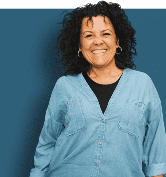 A photo of a woman in a blue denim shirt smiling at the camera