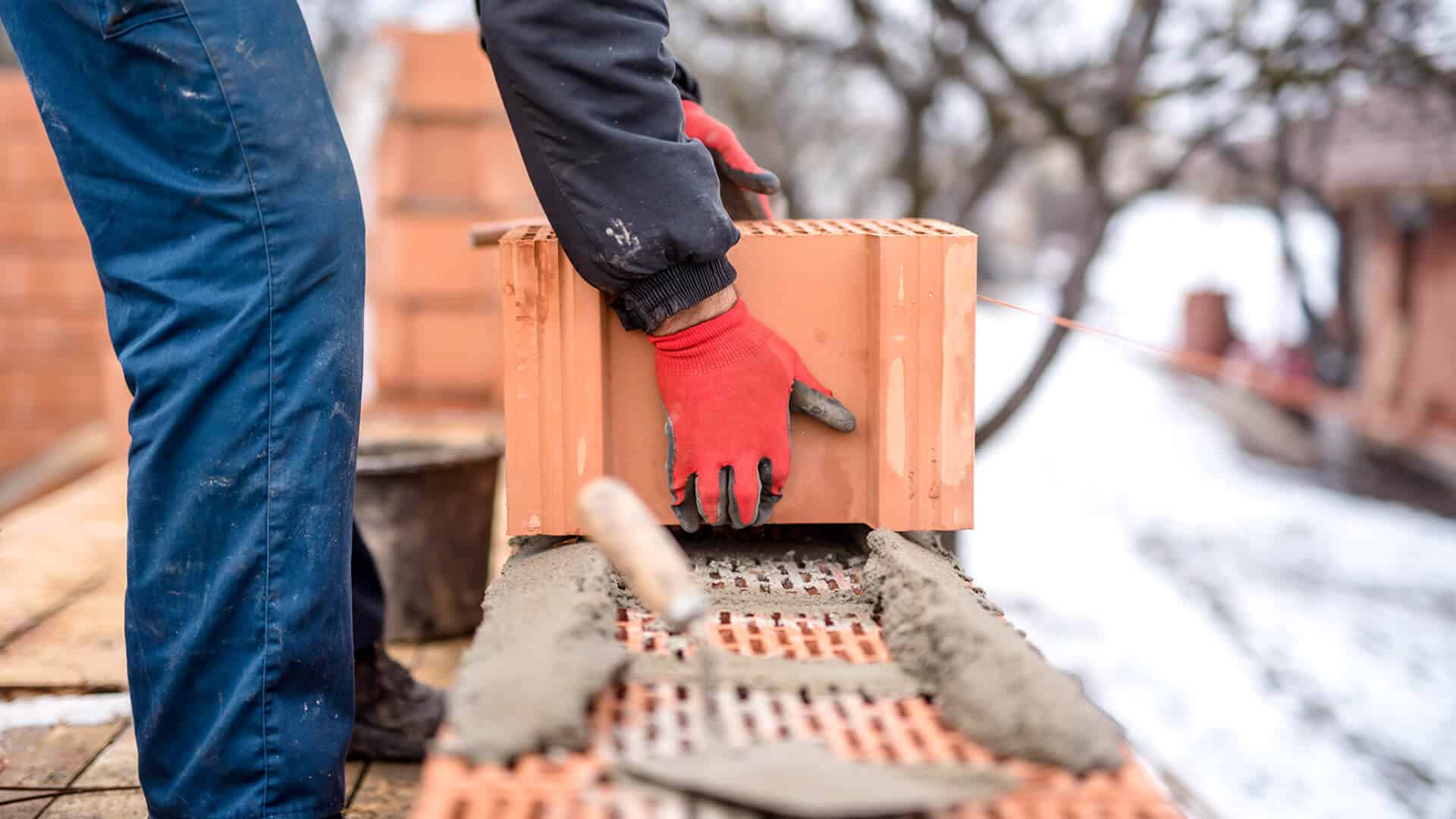 Your Guide to Keeping Projects On Time and On Budget Alt Tag: A bricklayer laying bricks on a construction project