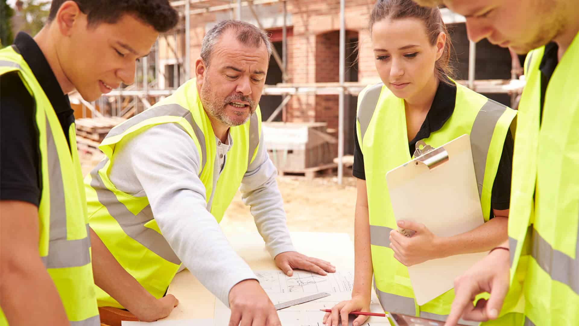 A group of building professionals discussing job safety on a construction site.