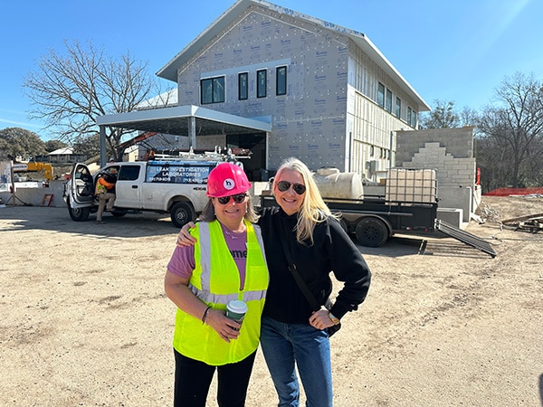 Two representatives of Home AId stand in front of a home under construction