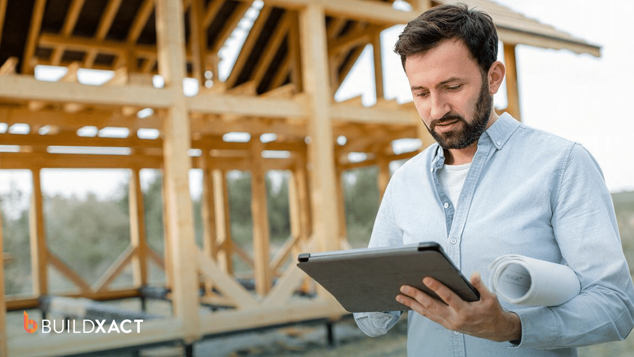 Residential builder logging construction costs and hours on a tablet at an active job site