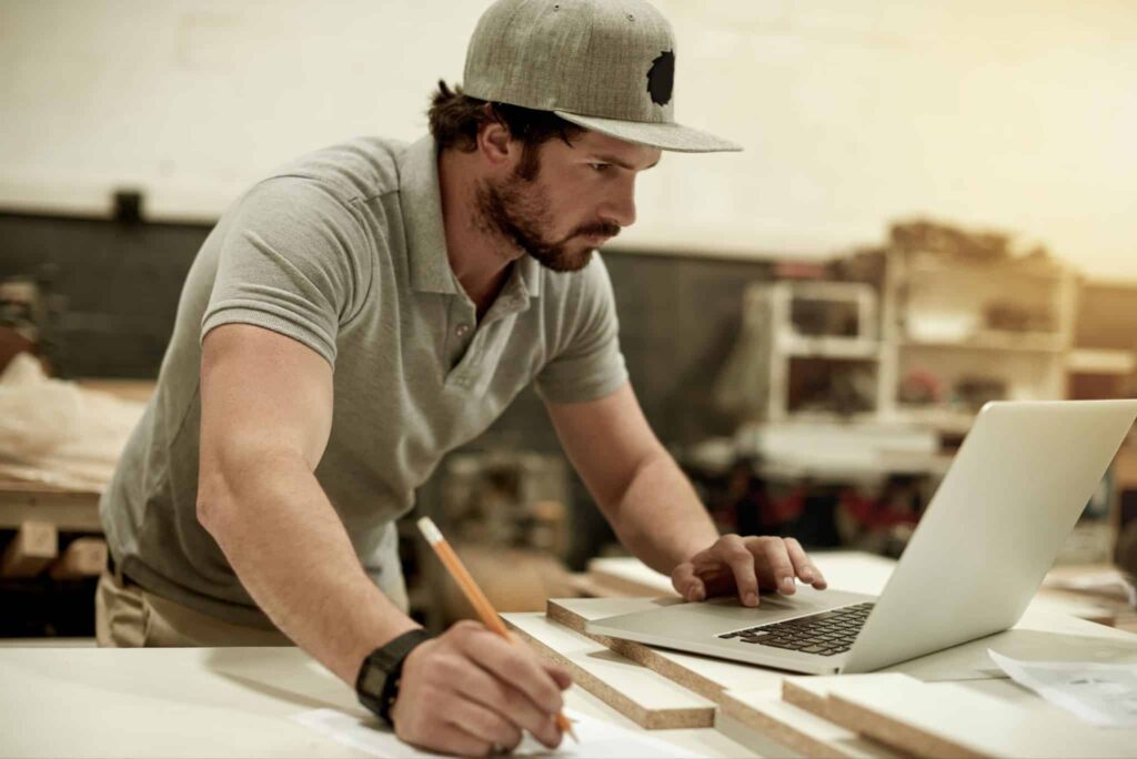 Builder working on a laptop and manually