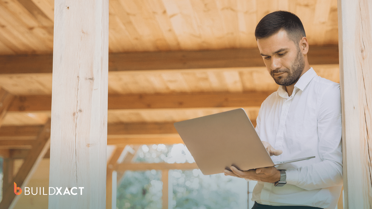 Residential builder reviewing job costs and budget tracking on a laptop at a construction site, evaluating alternatives to Houzz Pro
